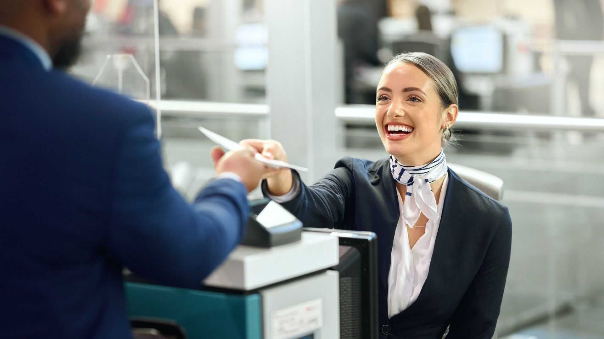 Airport check-in agent handing boarding passes to passengers at a dedicated group charter flight counter.